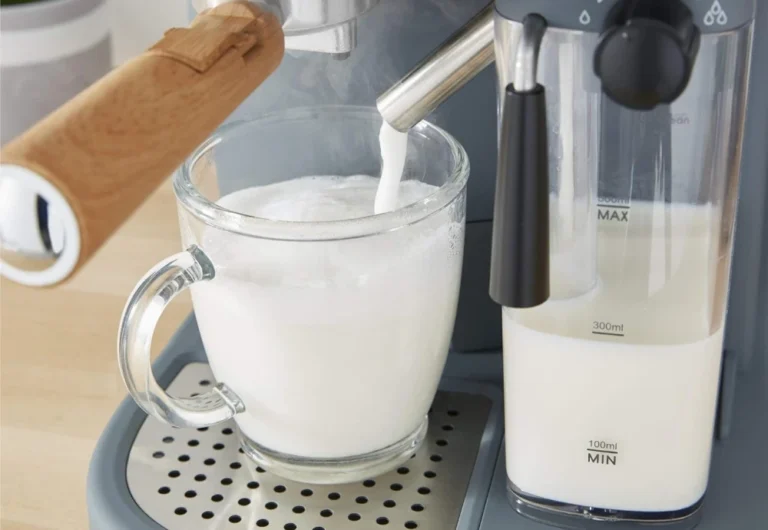 Frothy milk being poured from espresso machine steamer.