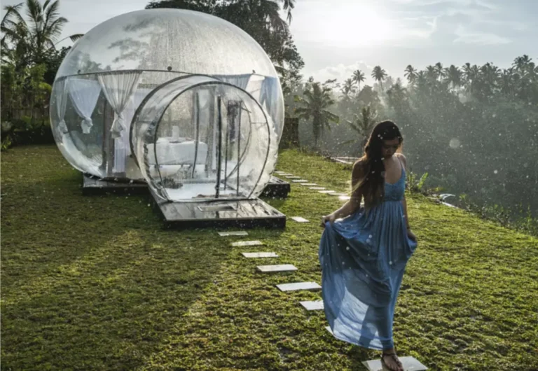 Woman walking towards transparent bubble tents in rain.