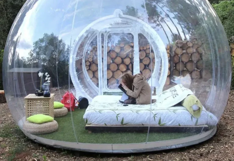 Woman reading inside transparent garden bubble tent.