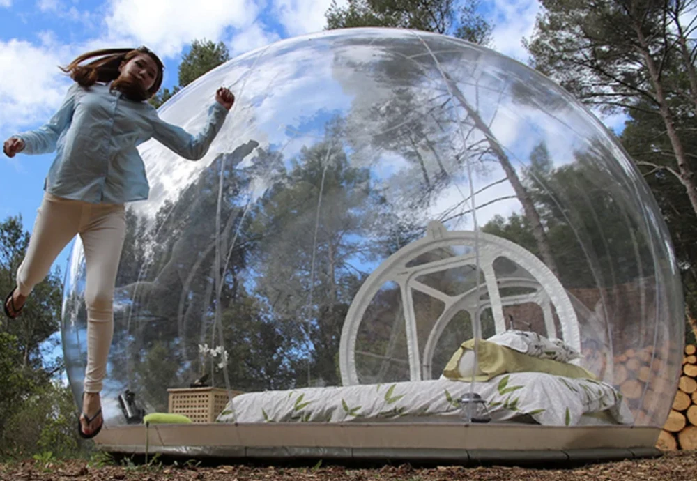 Woman jumping near outdoor transparent bubble tent.