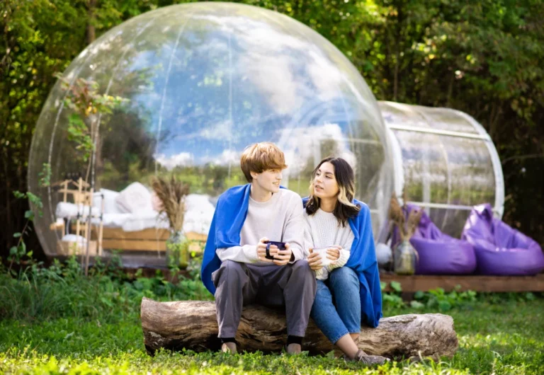 Couple chatting by transparent garden domes, nature retreat.