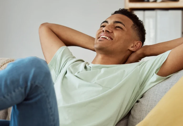 Young man relaxing on couch, smiling contentedly.