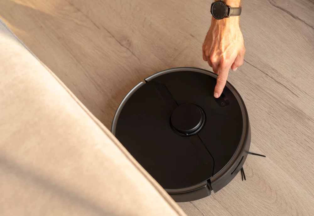 Person activating a black robotic vacuum cleaner.