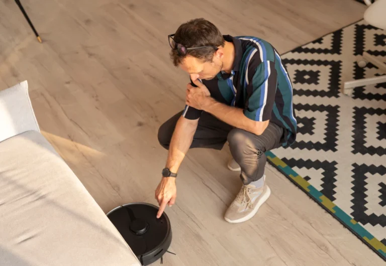 Man programming robotic vacuum cleaner at home.