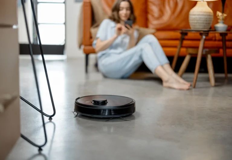 Woman relaxing while robotic vacuum cleans modern living room.